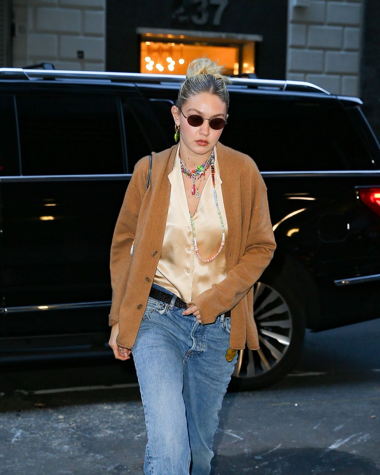 Who made Gigi Hadid's gray cardigan sweater, blue jeans, brown handbag, and  beige shoes? – OutfitID