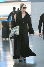 Angelina Jolie in a Chic Long Black Overcoat and Carrying a Dior Handbag at JFK Airport in New York 09/25/2023