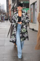 Chrissy Teigen in a Floral Print Raincoat, Denim and a Cap in New York 01/25/2024