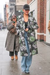 Chrissy Teigen in a Floral Print Raincoat, Denim and a Cap in New York 01/25/2024