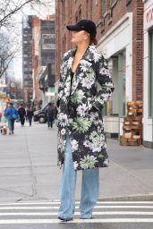 Chrissy Teigen in a Floral Print Raincoat, Denim and a Cap in New York 01/25/2024