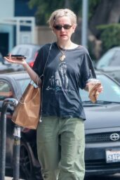 Julia Garner sitting at outdoor cafe in graphic tee and green trousers, Los Angeles March 2026 street style