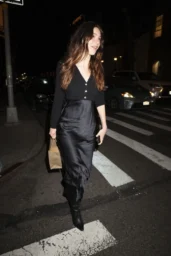 Camila Morrone walking in a black mixed-texture dress and pointed boots in New York, April 2026