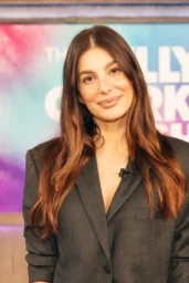 Camila Morrone waving in a black tailored suit at The Kelly Clarkson Show in Studio 6A April 2026