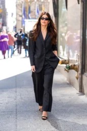 Camila Morrone walking in Midtown New York City in a charcoal suit and black sunglasses, April 2026