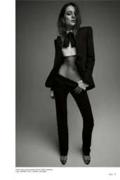 Charlotte Lawrence posing in black Balenciaga suit with white cropped shirt and bow tie, striped Manolo Blahnik shoes for Elle US Women in Music editorial, April 2026