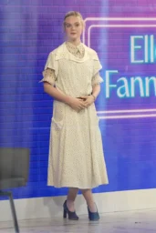 Elle Fanning standing on The Today Show set in New York April 2026 wearing a cream Rabanne midi dress with layered collar and pockets and dark Tods leather pumps