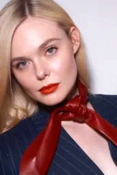 Elle Fanning posing in Givenchy Fall 2026 pinstripe suit with red leather neck scarf, April 2026