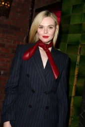 Elle Fanning posing in a navy pinstripe suit with a red neck tie at The Bowery Hotel afterparty in New York City, April 8, 2026