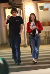 Olivia Rodrigo smiling while walking in a red cardigan and Repetto ballet flats in Los Angeles, April 2026
