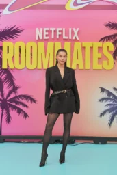 Paris Berelc posing in a black belted blazer dress with sheer tights at the Roommates L.A. premiere in Los Angeles April 13 2026